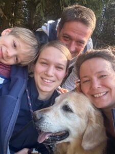 eine Familie mit Vater, Mutter, Tochter und Sohn und dem Golden Retriver Linus in der Mitte als wichtiges Familienmitglied