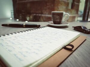 a journal written on, a montblanc-filler and a cup of espresso beside the journal