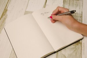 a female hand holding a pen and writing in a journal