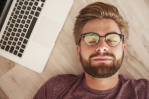 a man with laptop nex to him trying to sleep