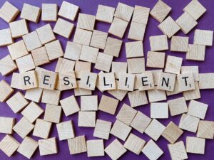 wodden puzzleparts with letters on them which are composed to the word resilience