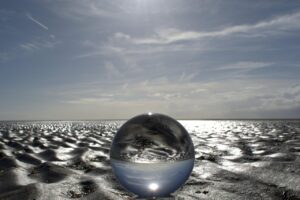 a round glas-kugel on the beach, sunny weather spreading the impression of clarity